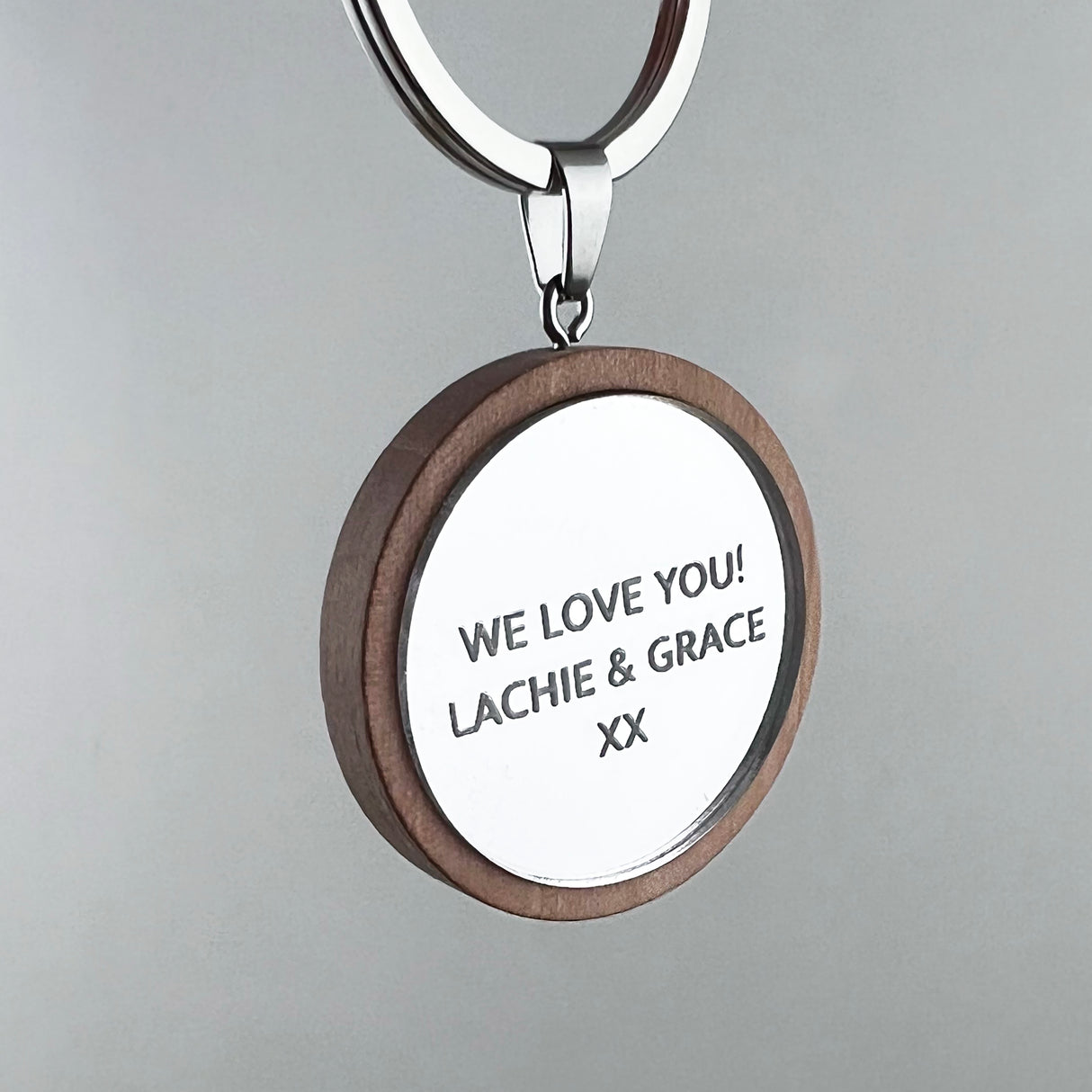 Keychain with engraved message 'WE LOVE YOU! LACHIE & GRACE XX' on a grey background